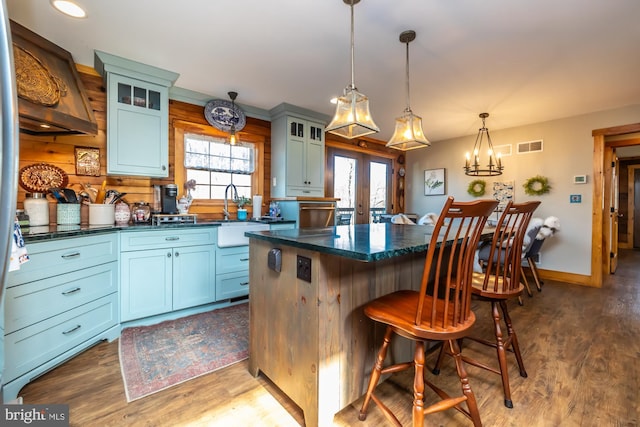 kitchen featuring french doors, dark hardwood / wood-style floors, decorative light fixtures, a kitchen bar, and a kitchen island