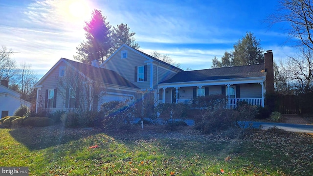 view of front of home featuring a garage, covered porch, and a front lawn