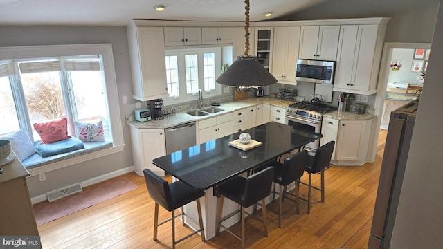 kitchen with white cabinets, appliances with stainless steel finishes, light stone counters, and sink