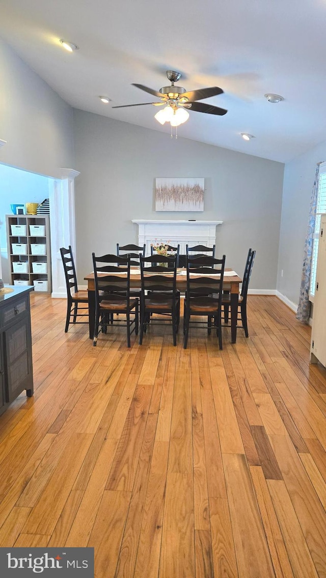 dining room with ceiling fan, light hardwood / wood-style flooring, and vaulted ceiling