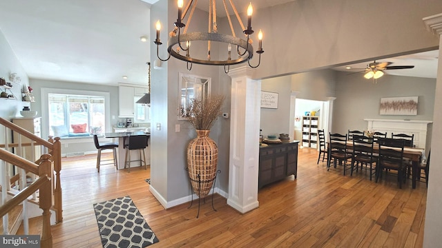 dining area with ceiling fan with notable chandelier, lofted ceiling, and light wood-type flooring