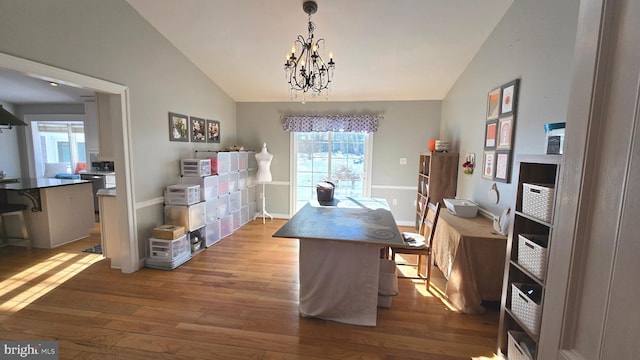 dining room featuring vaulted ceiling, light hardwood / wood-style flooring, and a notable chandelier