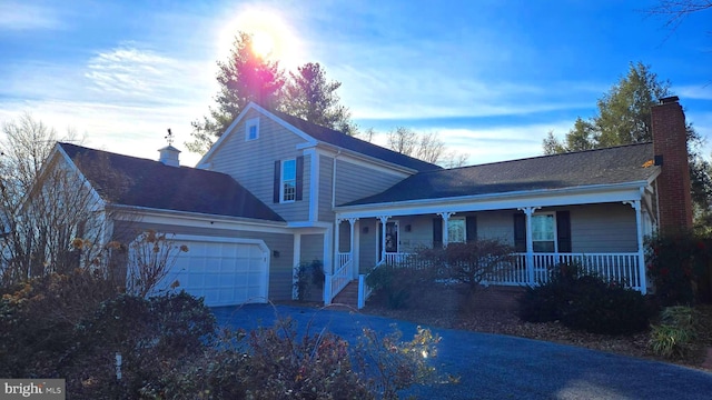 view of property with covered porch and a garage