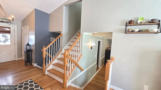 entryway with hardwood / wood-style floors, vaulted ceiling, and a notable chandelier