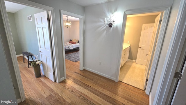 hallway featuring a notable chandelier and light wood-type flooring