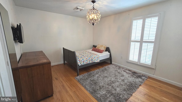 bedroom with hardwood / wood-style flooring and an inviting chandelier