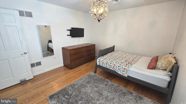 bedroom with an inviting chandelier and hardwood / wood-style flooring