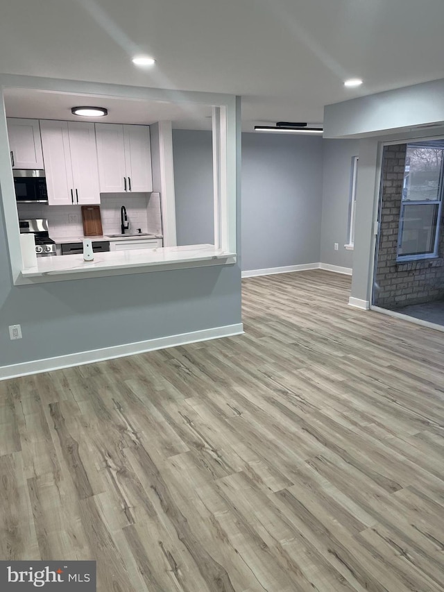 unfurnished living room featuring sink and light hardwood / wood-style floors