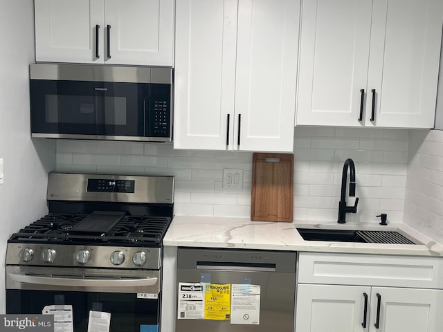 kitchen with white cabinetry, appliances with stainless steel finishes, sink, and backsplash