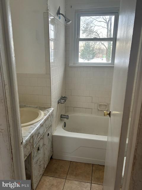 bathroom featuring tile patterned flooring, tiled shower / bath combo, and vanity