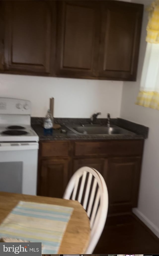 kitchen featuring dark brown cabinetry, white range with electric cooktop, and sink