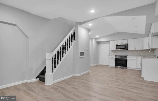 kitchen with white cabinetry, backsplash, appliances with stainless steel finishes, and light hardwood / wood-style flooring