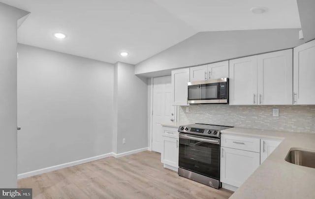 kitchen featuring white cabinetry, lofted ceiling, and appliances with stainless steel finishes