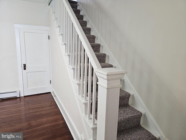 staircase with a baseboard heating unit and hardwood / wood-style flooring