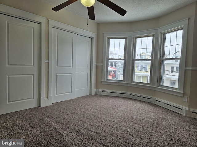 unfurnished bedroom featuring ceiling fan, a baseboard radiator, a textured ceiling, and carpet