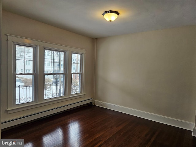 unfurnished room with baseboard heating, a wealth of natural light, and dark hardwood / wood-style floors