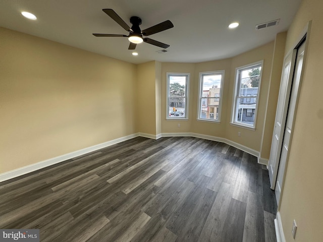 empty room with ceiling fan, dark hardwood / wood-style floors, and plenty of natural light