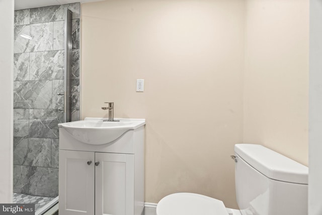 bathroom with toilet, tiled shower, and vanity