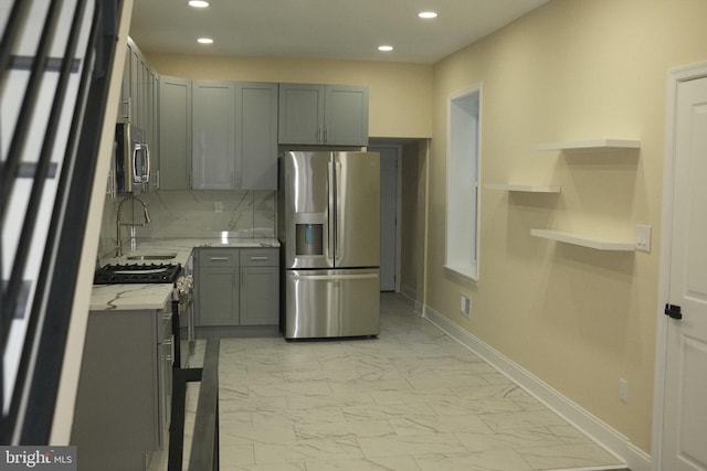 kitchen featuring light stone countertops, appliances with stainless steel finishes, gray cabinets, and tasteful backsplash