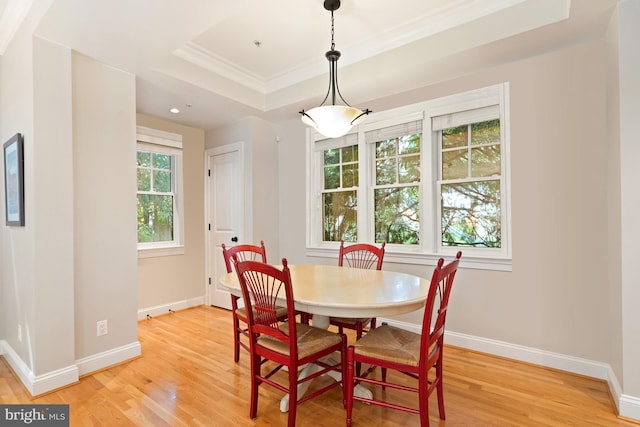 dining area with a raised ceiling, crown molding, and hardwood / wood-style flooring