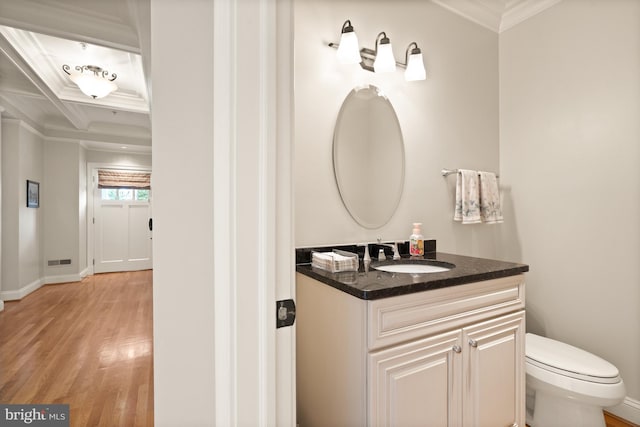 bathroom featuring coffered ceiling, toilet, hardwood / wood-style flooring, vanity, and ornamental molding