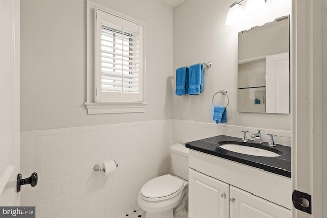 bathroom with vanity, toilet, and tile walls