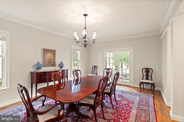 dining space with french doors, light hardwood / wood-style floors, crown molding, and a notable chandelier