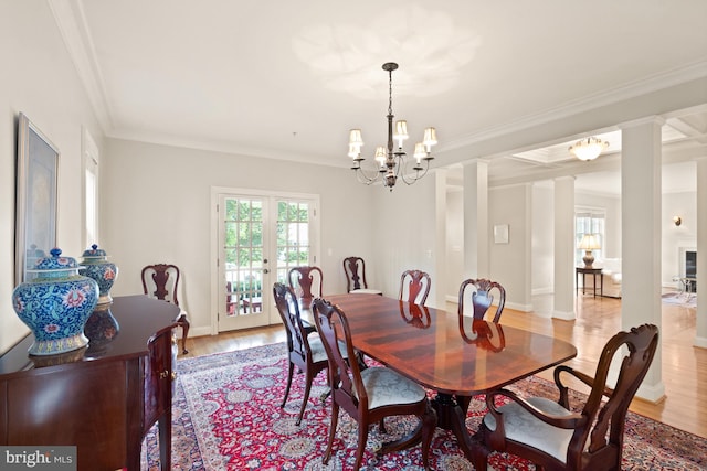 dining room featuring french doors, ornamental molding, decorative columns, a chandelier, and light wood-type flooring