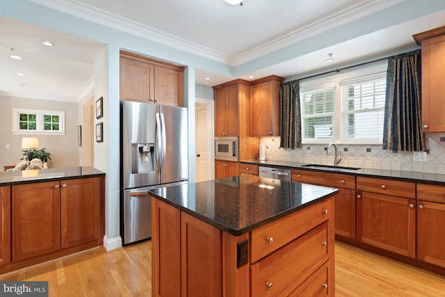 kitchen with backsplash, sink, light hardwood / wood-style flooring, appliances with stainless steel finishes, and a kitchen island