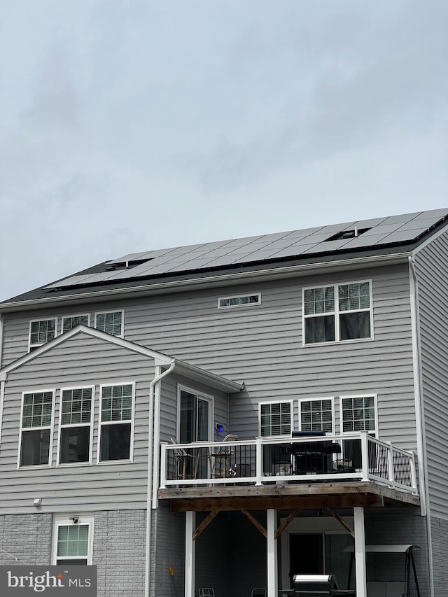 back of house featuring a wooden deck and roof mounted solar panels