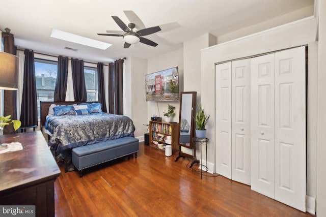 bedroom featuring ceiling fan, a closet, dark wood-type flooring, and a skylight