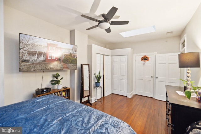 bedroom featuring a skylight, ceiling fan, and dark wood-type flooring