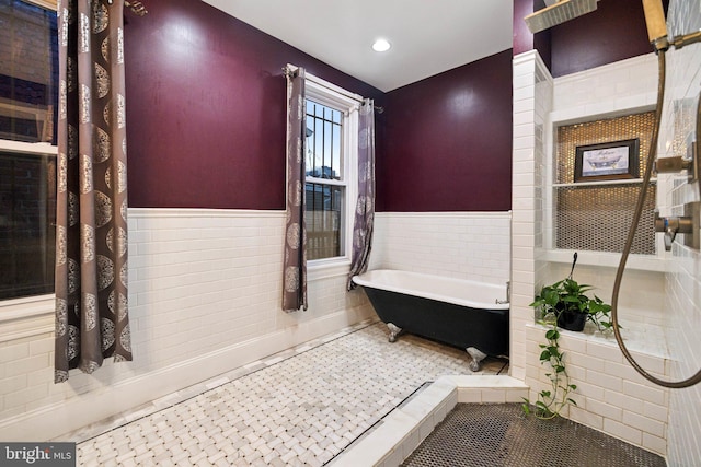 bathroom featuring tile patterned flooring, a bathtub, and tile walls