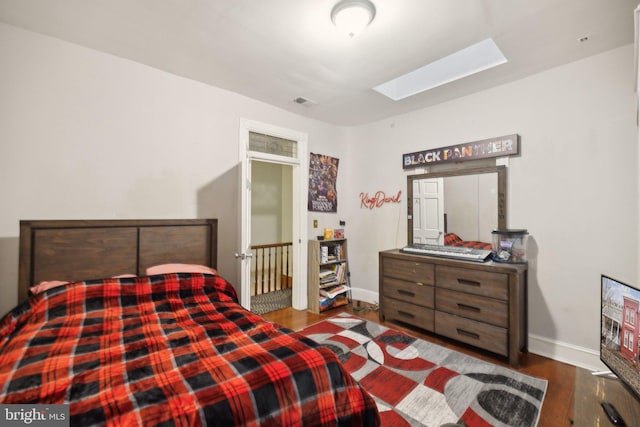 bedroom with a skylight and dark hardwood / wood-style flooring