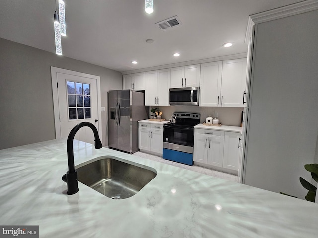 kitchen featuring pendant lighting, white cabinetry, sink, and stainless steel appliances