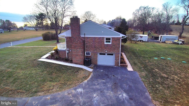 property exterior at dusk with a lawn, central AC unit, and a garage