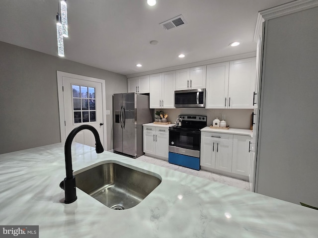 kitchen featuring white cabinets, appliances with stainless steel finishes, pendant lighting, and sink