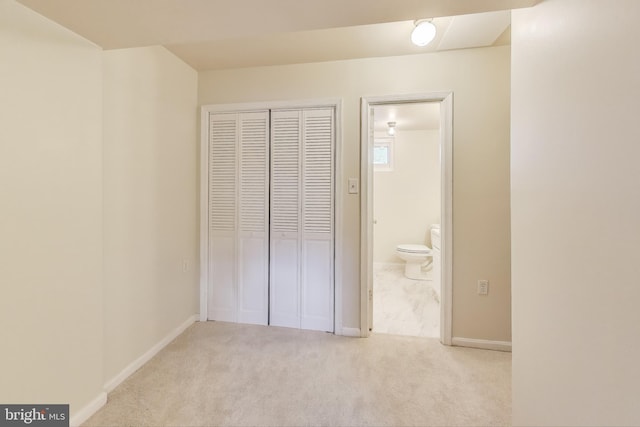 unfurnished bedroom featuring ensuite bathroom, light colored carpet, and a closet