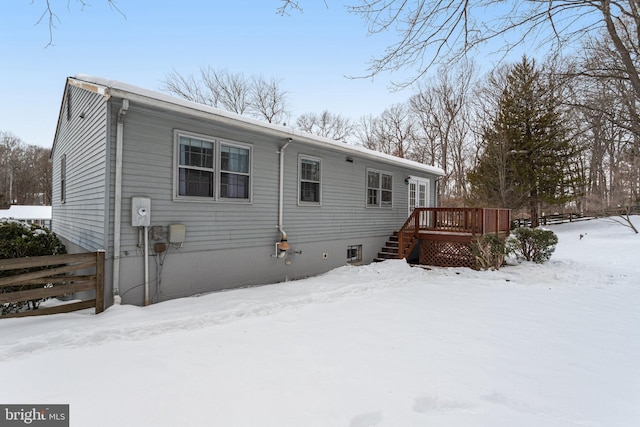 snow covered back of property featuring a wooden deck