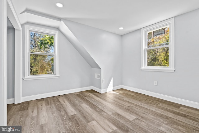 bonus room with light wood-type flooring and vaulted ceiling