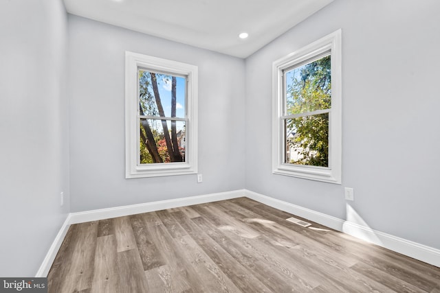 empty room with light hardwood / wood-style floors and plenty of natural light