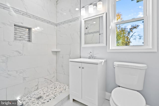 bathroom featuring toilet, vanity, plenty of natural light, and tiled shower