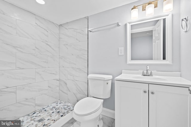 bathroom featuring tiled shower, vanity, and toilet