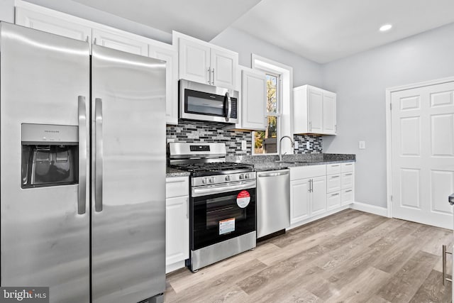 kitchen featuring white cabinets, sink, stainless steel appliances, and dark stone countertops