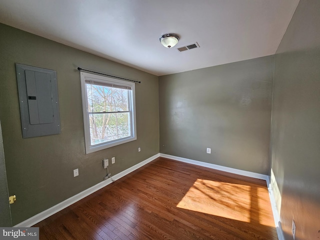 unfurnished room with electric panel and hardwood / wood-style floors