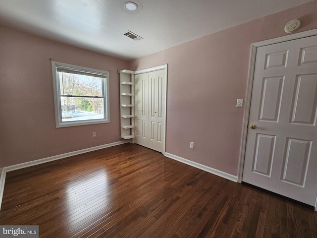 unfurnished bedroom featuring a closet and dark wood-type flooring