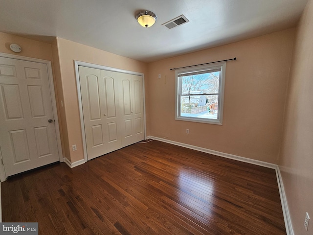 unfurnished bedroom featuring dark wood-type flooring and a closet