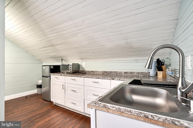 kitchen featuring sink, dark hardwood / wood-style floors, stainless steel fridge, vaulted ceiling, and white cabinets