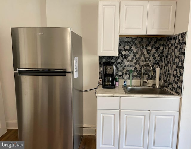 kitchen with white cabinets, stainless steel fridge, sink, and tasteful backsplash