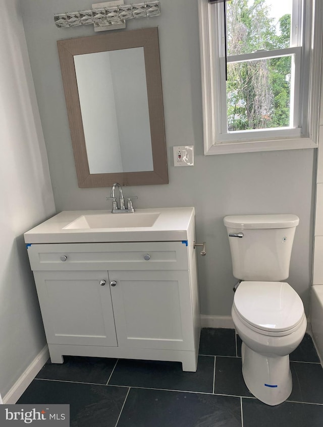 bathroom featuring tile patterned floors, vanity, toilet, and a bathing tub